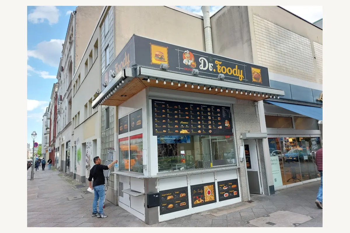 Dr. foody – Eckfassade mit Speisetafeln und bedruckten Fensterflächen.